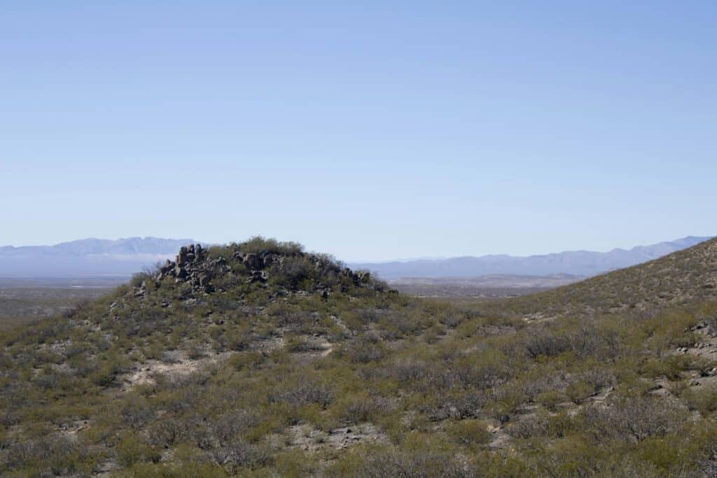 Natural desert landscape with rocky hills and sparse vegetation in a wide-open area.