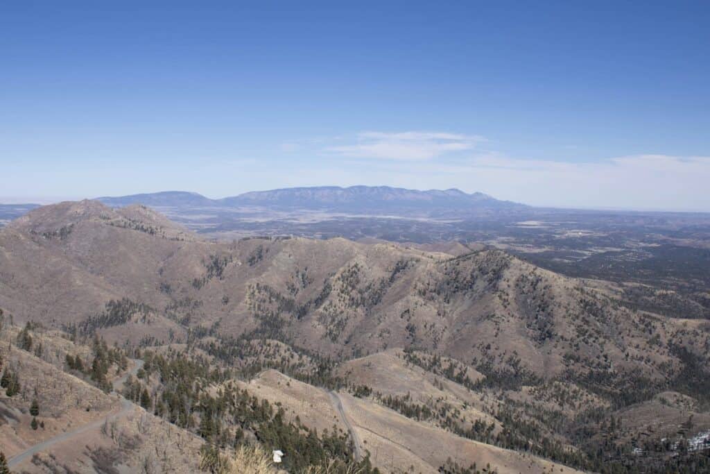Hilly landscape with rugged mountains and sparse vegetation, under clear blue sky, representing land surveying in mountainous terrain.